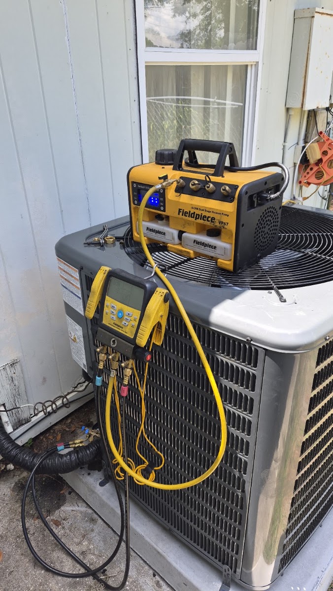 New condenser mid-install on a concrete pad with tools and a level on top