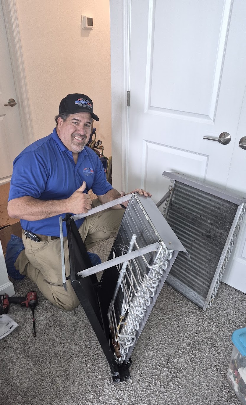 Technician on a ladder in a home attic sealing silver ductwork with a headlamp on